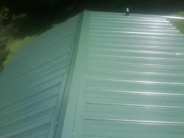 New green metal panels meeting at the ridge of a roof in Lennon