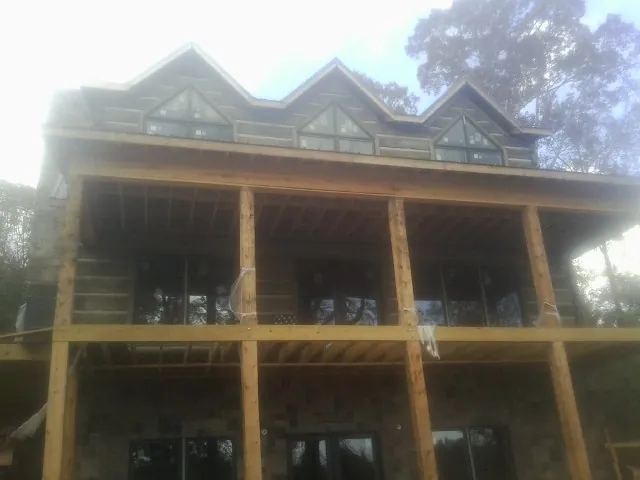 Dormers and porch framing on a large log home under construction — Roof Coating work by our crew in Lennon
