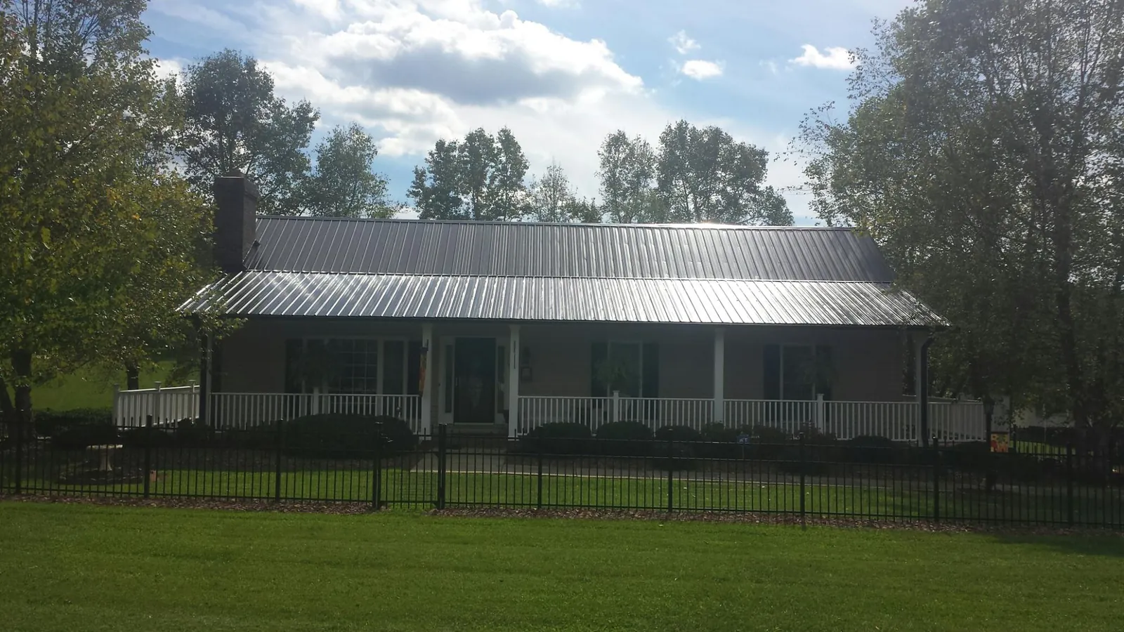 Gray metal roof on a brick ranch with a full width front porch — Gutter Guard Installation work by our crew in Lennon