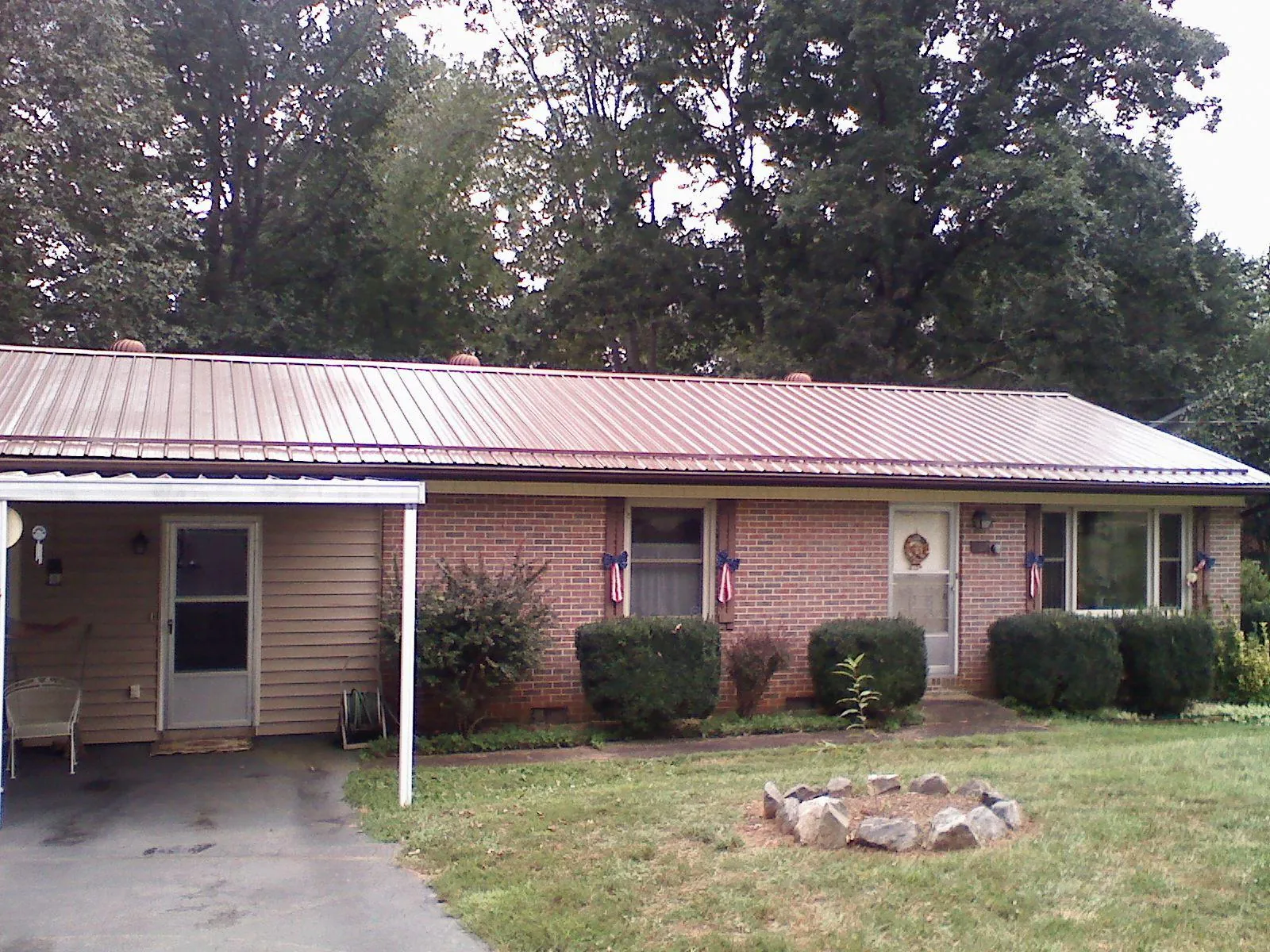 Bronze metal roof and carport on a brick ranch home — Roof Repair work by our crew in Lennon