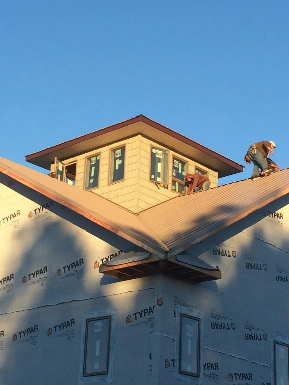 Roofers working around a rooftop cupola on a new metal roof at sunset — Roof Waterproofing in Lennon by Roofing Brothers